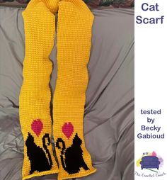 a pair of yellow crocheted socks with black cats on them sitting on top of a bed