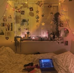 a laptop computer sitting on top of a bed in a room with lights strung from the ceiling