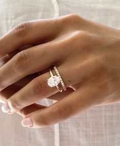 a woman's hand with a diamond ring on her left hand and the other hand holding an engagement ring