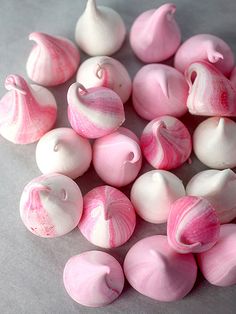 some pink and white candies are on a gray surface with one candy in the middle