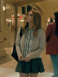 a woman in a skirt and jacket standing on the sidewalk