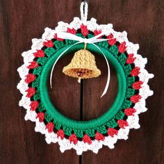 a crocheted christmas wreath with a bell hanging from it