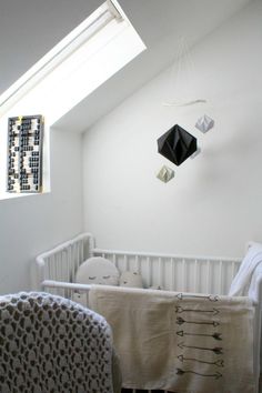 a white crib with a black and white blanket on it next to a window