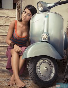 a woman sitting on the ground next to a motor scooter in front of stairs