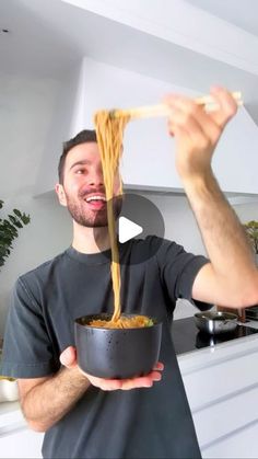 a man holding a bowl of noodles in his hands