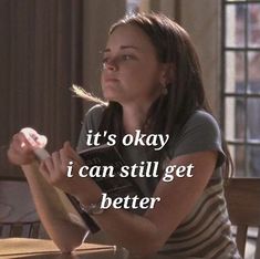 a woman sitting at a wooden table with a quote on it that reads, it's okay i can still get better