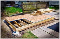 some wooden boards laying on the ground in front of a fence and building materials that are being built