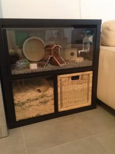 a large black shelf with baskets and other items in it next to a white couch