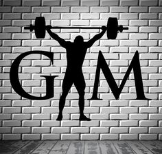 a man lifting a barbell with the word gym on it in front of a brick wall