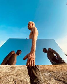 a man standing in front of a mirror with his hands on the ground and two other men behind him