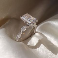 a diamond ring sitting on top of a white satin covered table cloth with the light shining through it