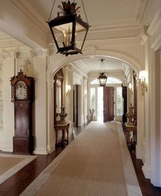 a large hallway with an archway and clock on the wall, along with two lamps hanging from the ceiling