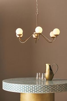 a table with a pitcher and three glasses on it in front of a brown wall