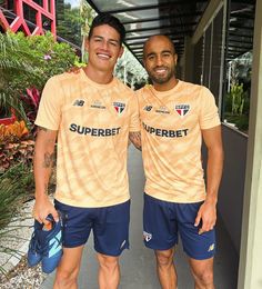 two men standing next to each other wearing orange and blue shirts with the words superb written on them