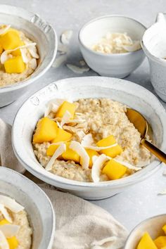 bowls of oatmeal with mango and coconut on the side, ready to be eaten