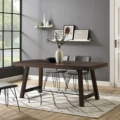 a dining room table and chairs in front of a gray wall with pictures on it