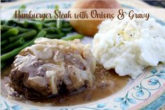 a plate with mashed potatoes, meat and gravy on it next to green beans