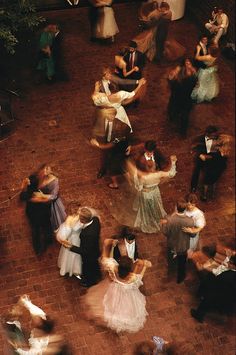 a group of people standing around each other on top of a brick floor in a courtyard