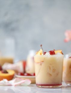 two glasses filled with ice cream and fruit sitting on a table next to other desserts