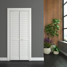 an empty room with two potted plants on the floor and a white door in the middle