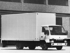 a white box truck parked in front of a building with windows on it's sides