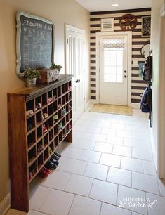 a hallway with a chalkboard on the wall next to a book shelf and shoe rack