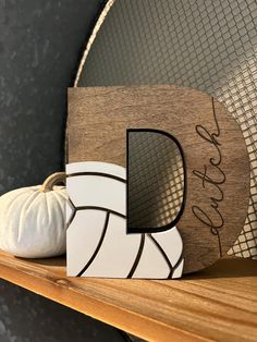 a wooden block with the letter d on it next to a white pumpkin and net