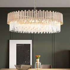 a chandelier hanging over a dining table in a room with dark green walls