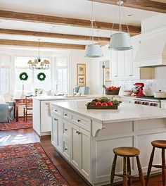 a large kitchen with white cabinets and an island in the middle is decorated with wreaths