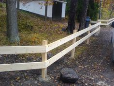 a car parked on the side of a road next to a wooden fence and trees