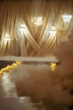 candles are lit in the middle of a room with drapes on the walls and curtains