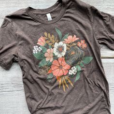 This lightweight, tri-blend tee is so comfy with just the right amount of stretch. The heathered fabric and soft print creates the perfect vintage feel with a fitted look. Oatmeal heather or brown heather colored tee with full color, hand drawn colorful bouquet printLove florals? Check out the other floral bouquet tee in the shop:https://fancythatdesignhouse.com/collections/tees/products/colorful-floral-teeTri-blend construction (50% polyester/25% combed ring-spun cotton/25% rayon)Contemporary/m Vintage Floral Print T-shirt For Fall, Multicolor Floral Print T-shirt For Fall, Multicolor Floral Print Graphic Tee Shirt, Retro Cotton T-shirt With Floral Print, Spring Bohemian T-shirt With Floral Print, Army Colors, Floral Tee, Colorful Bouquet, Light Blue Color