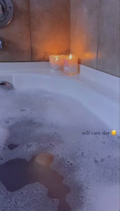 a bathtub filled with water next to a candle