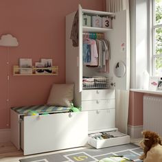 a child's bedroom with pink walls and white furniture, including a toy chest