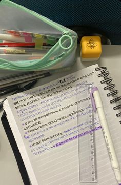 an open notebook sitting on top of a desk next to a pen and pencil holder