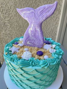 a blue and green cake with a mermaid tail on top