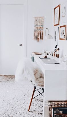 a white room with a chair, sink and pictures on the wall