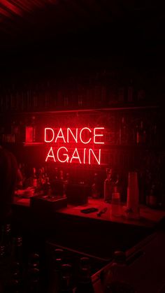 a red neon sign that reads dance again in the middle of a dark room with bottles