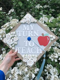 someone holding up a graduation cap that says, my turn to teach with an apple on it