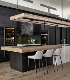 a modern kitchen with black cabinets and marble counter tops, bar stools and an island in the middle