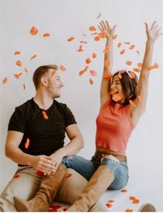 a man and woman sitting on the ground with confetti falling from their mouths