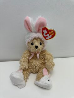 a teddy bear wearing a bunny hat and slippers sitting on a white counter top