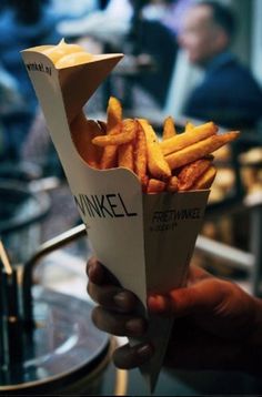 a person holding up a basket full of french fries