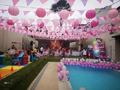 an outdoor party with pink and purple decorations, balloons and streamers hanging from the ceiling