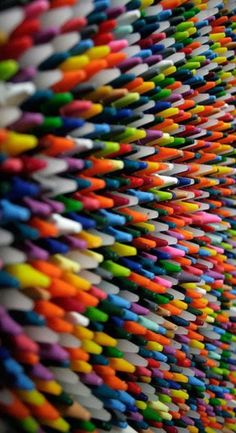 many colored pencils are stacked on top of each other in the same color scheme