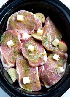 some meat and potatoes are in a black crock pot with pink border around the edges