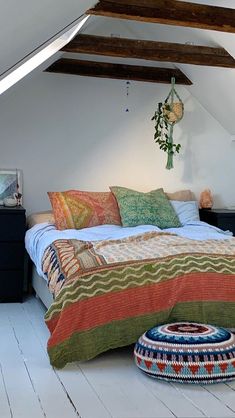 a bed with colorful blankets and pillows in a loft space next to an ottoman on the floor