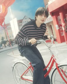 a young man riding a red bike down a street