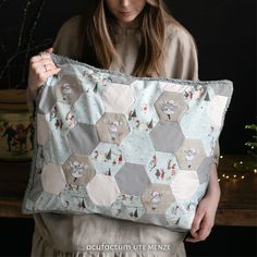 a woman holding up a pillow made out of hexagons