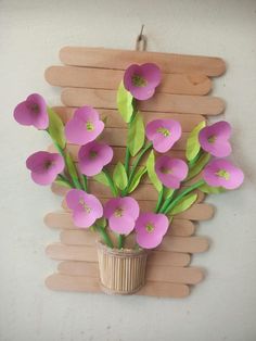 a vase filled with pink flowers sitting on top of a wooden peg board wall decoration